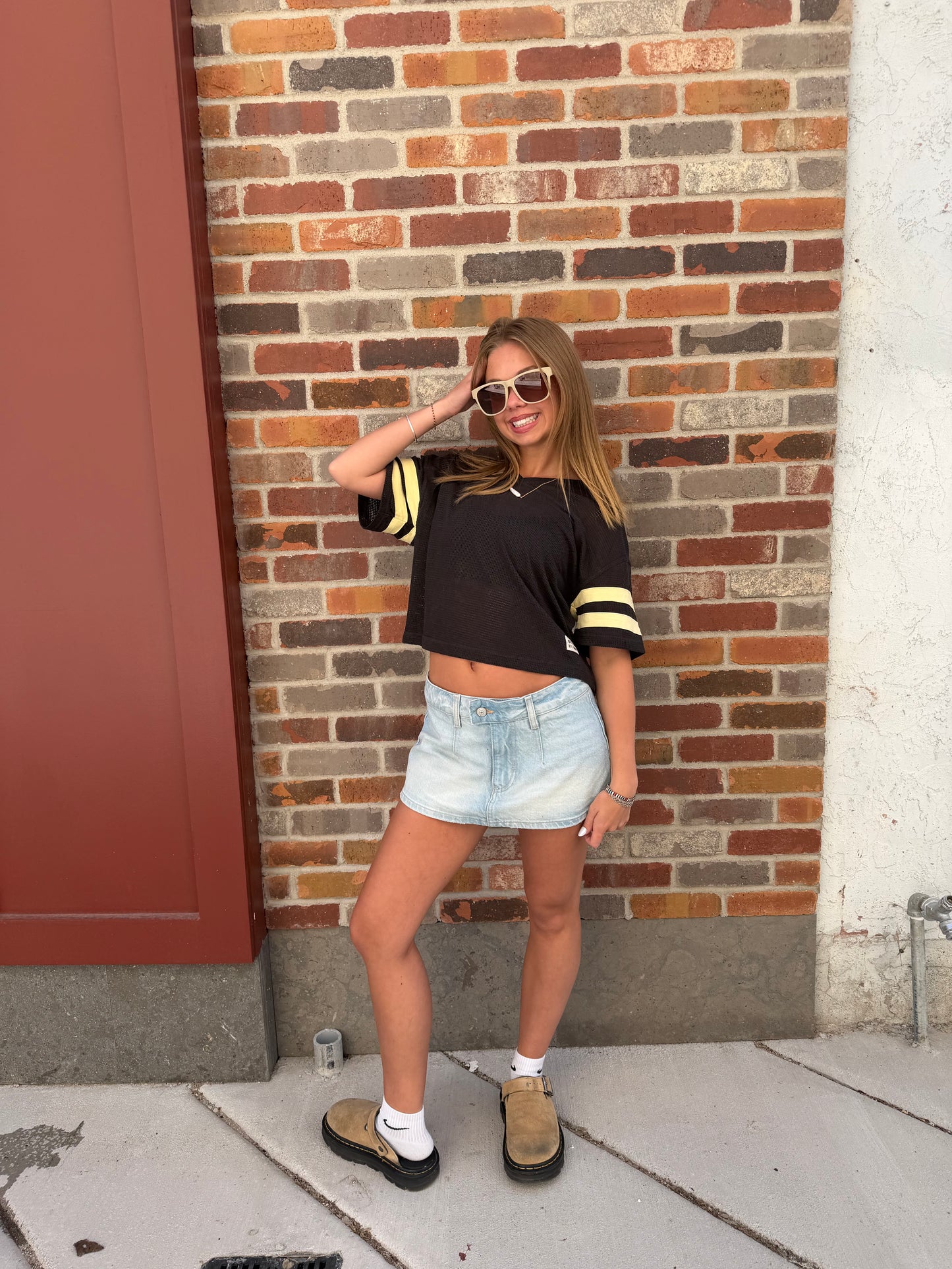 Person standing on a sidewalk with a brick wall background