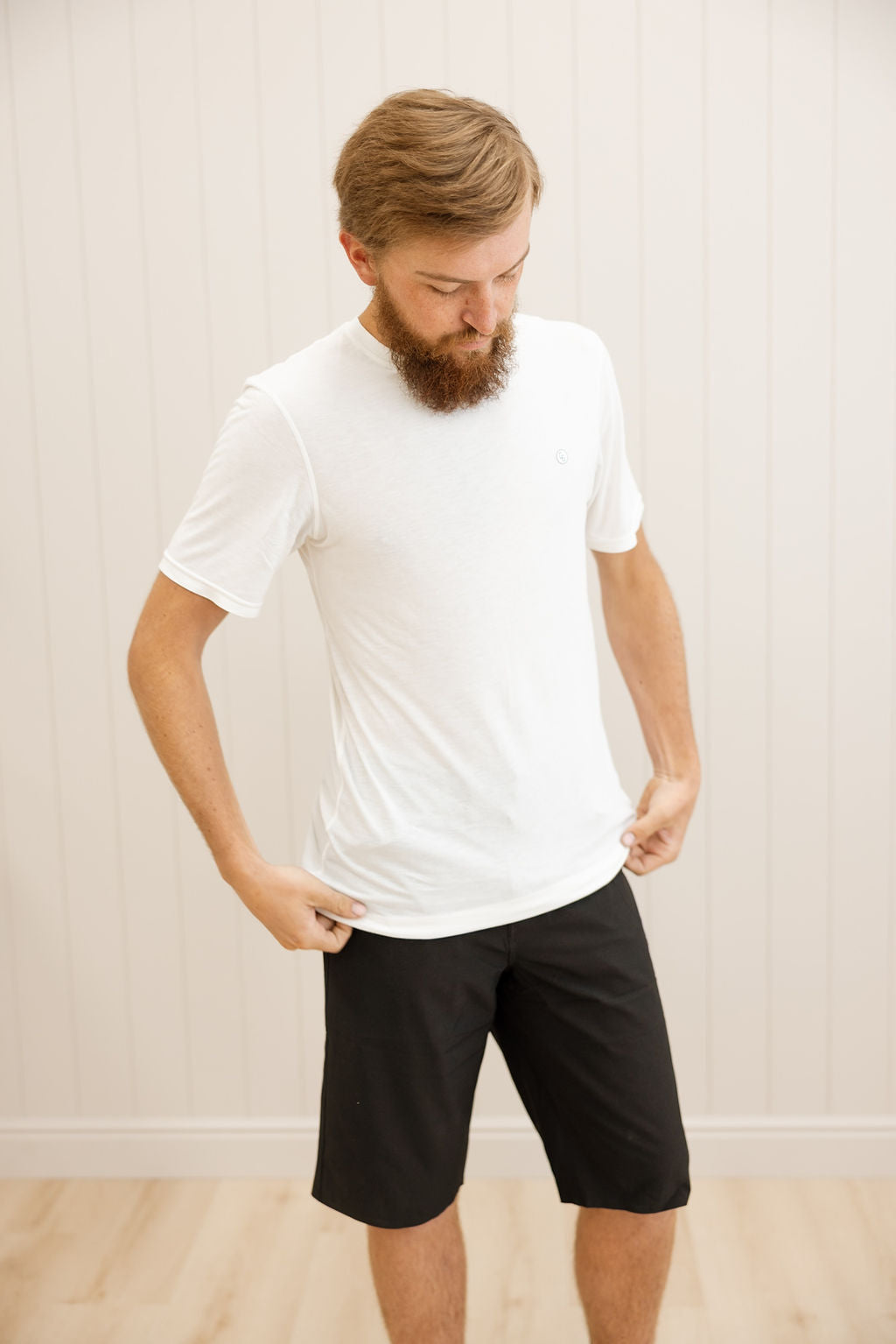 Man wearing a white t-shirt and black shorts against a plain background