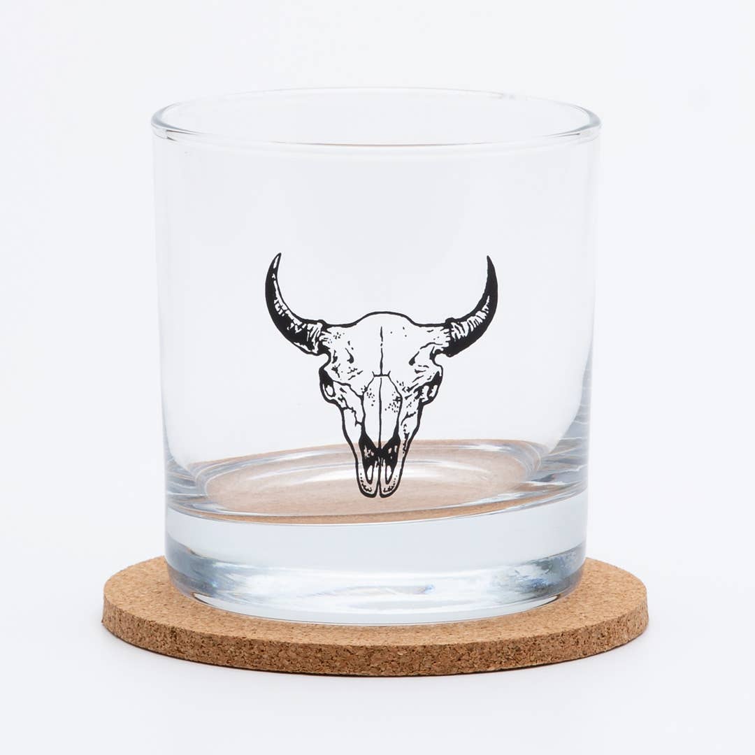 Clear glass tumbler with bull skull design on a cork coaster