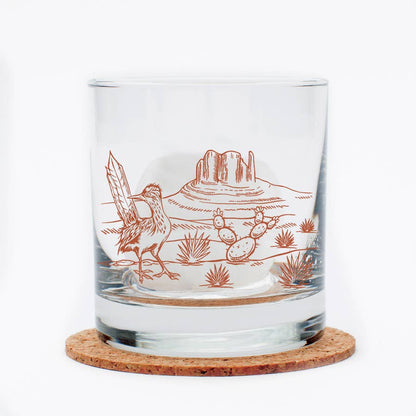 Clear glass tumbler with desert-themed engraving on a cork coaster