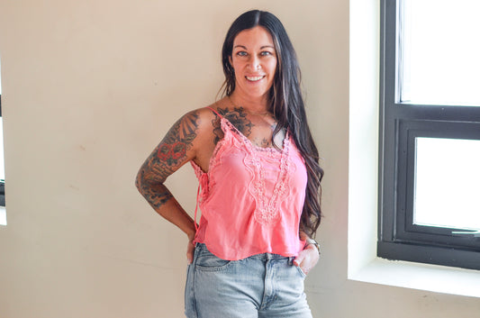 Woman wearing a pink top and jeans standing indoors.