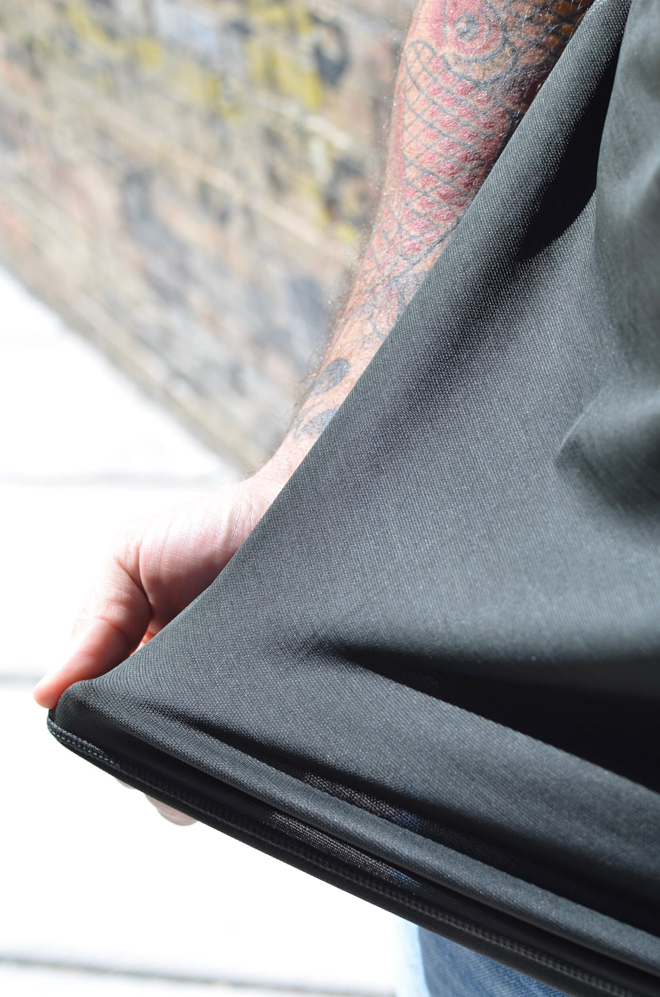Person holding a dark gray fabric with a blurred background