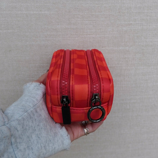Red checkered pouch with a zipper held by a person against a neutral background