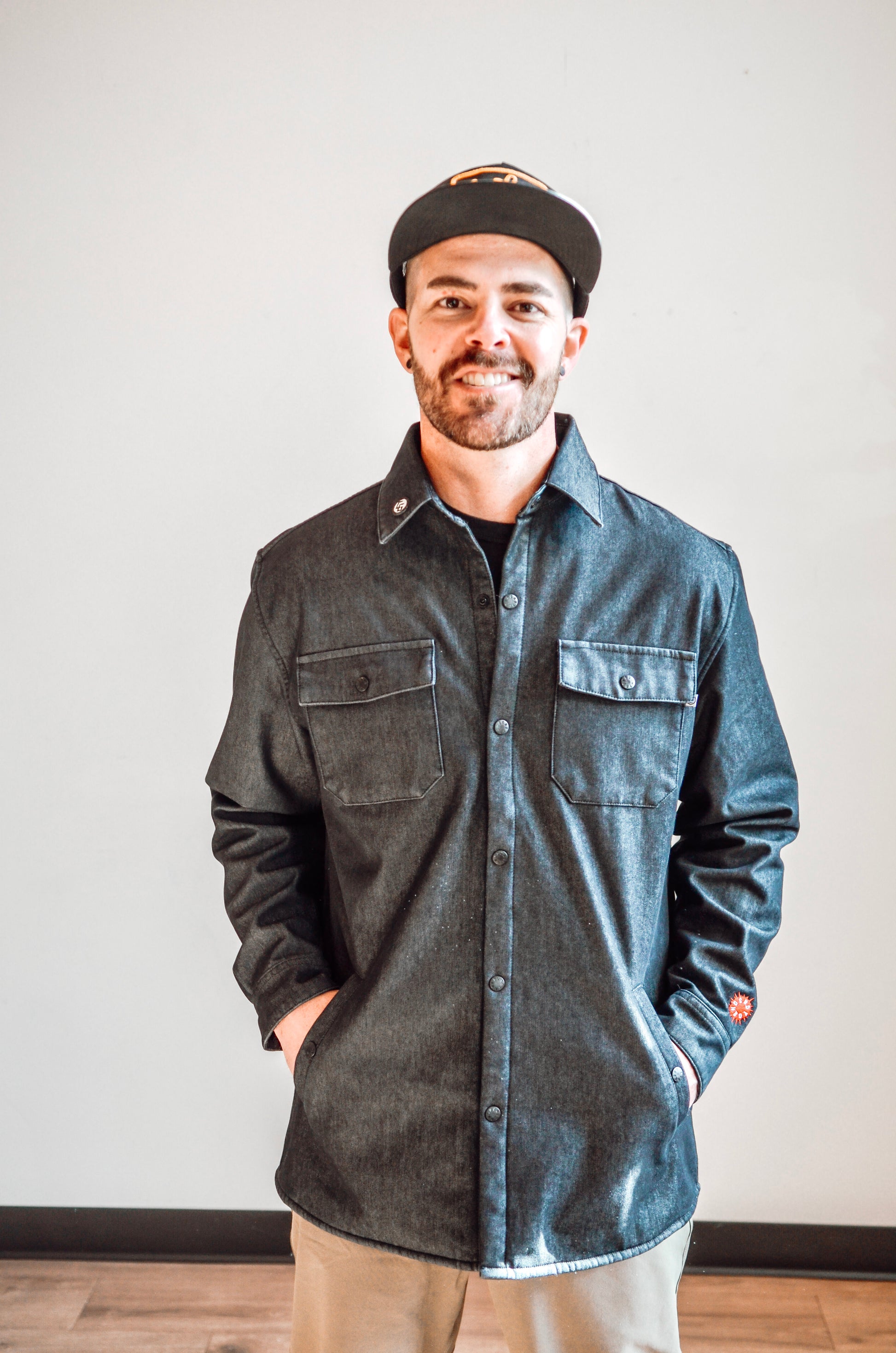 Man wearing a dark denim shirt and cap against a plain background