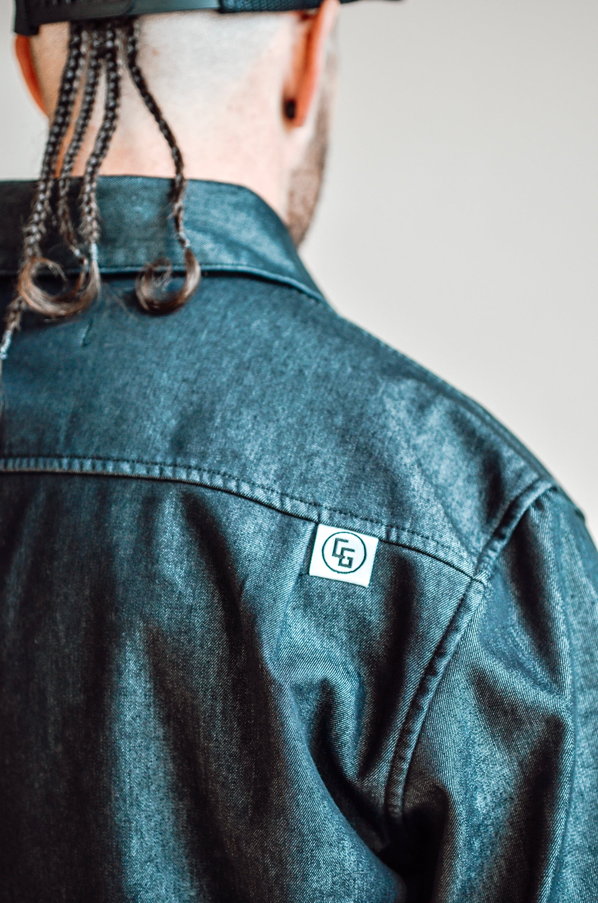 Person wearing a denim shirt with a brand logo on the chest.