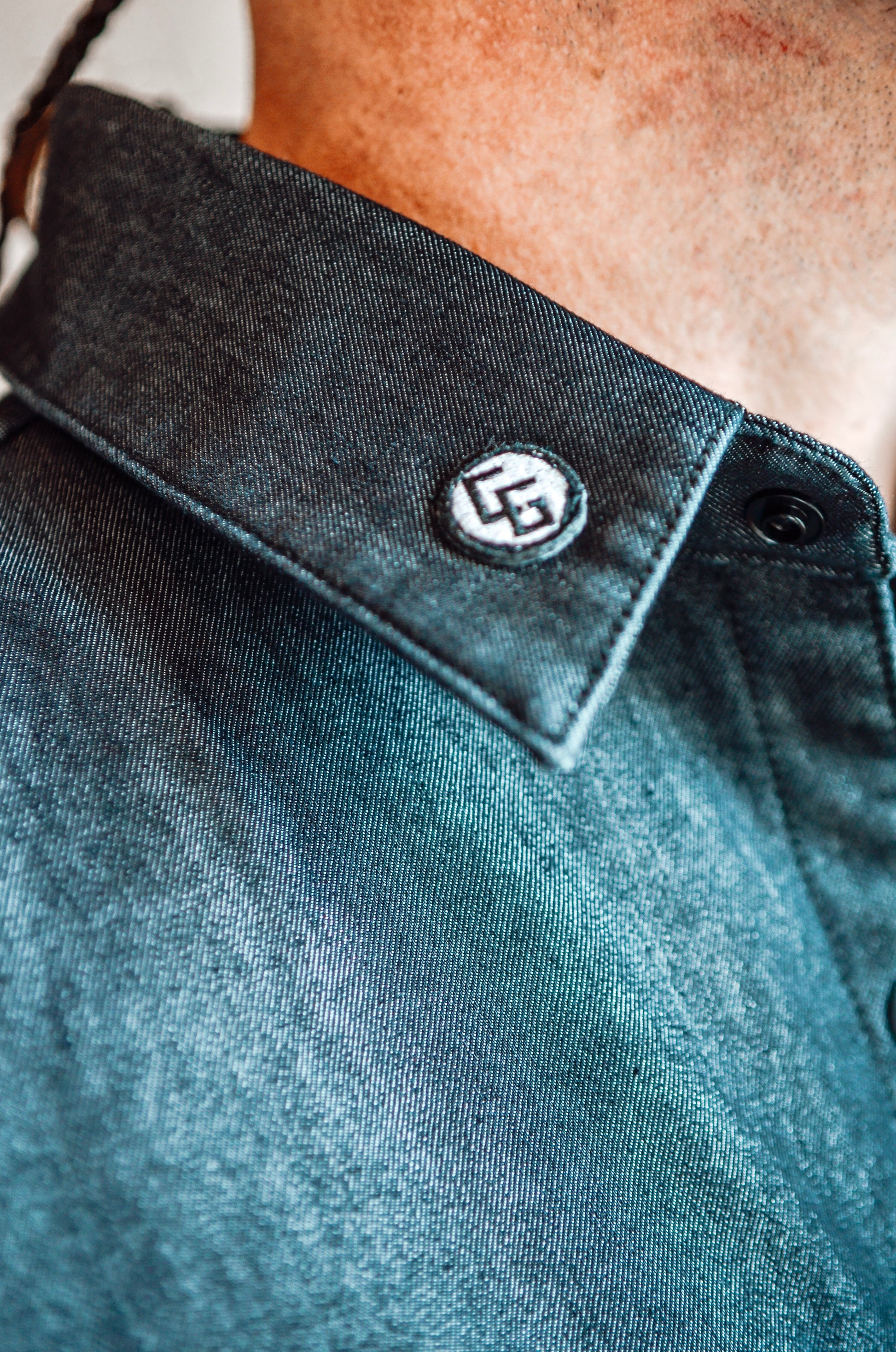Close-up of a dark blue shirt collar with a logo on a blurred background
