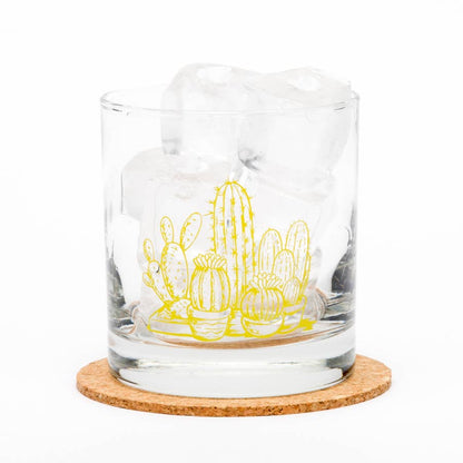 Clear glass tumbler with yellow cactus design on a cork coaster
