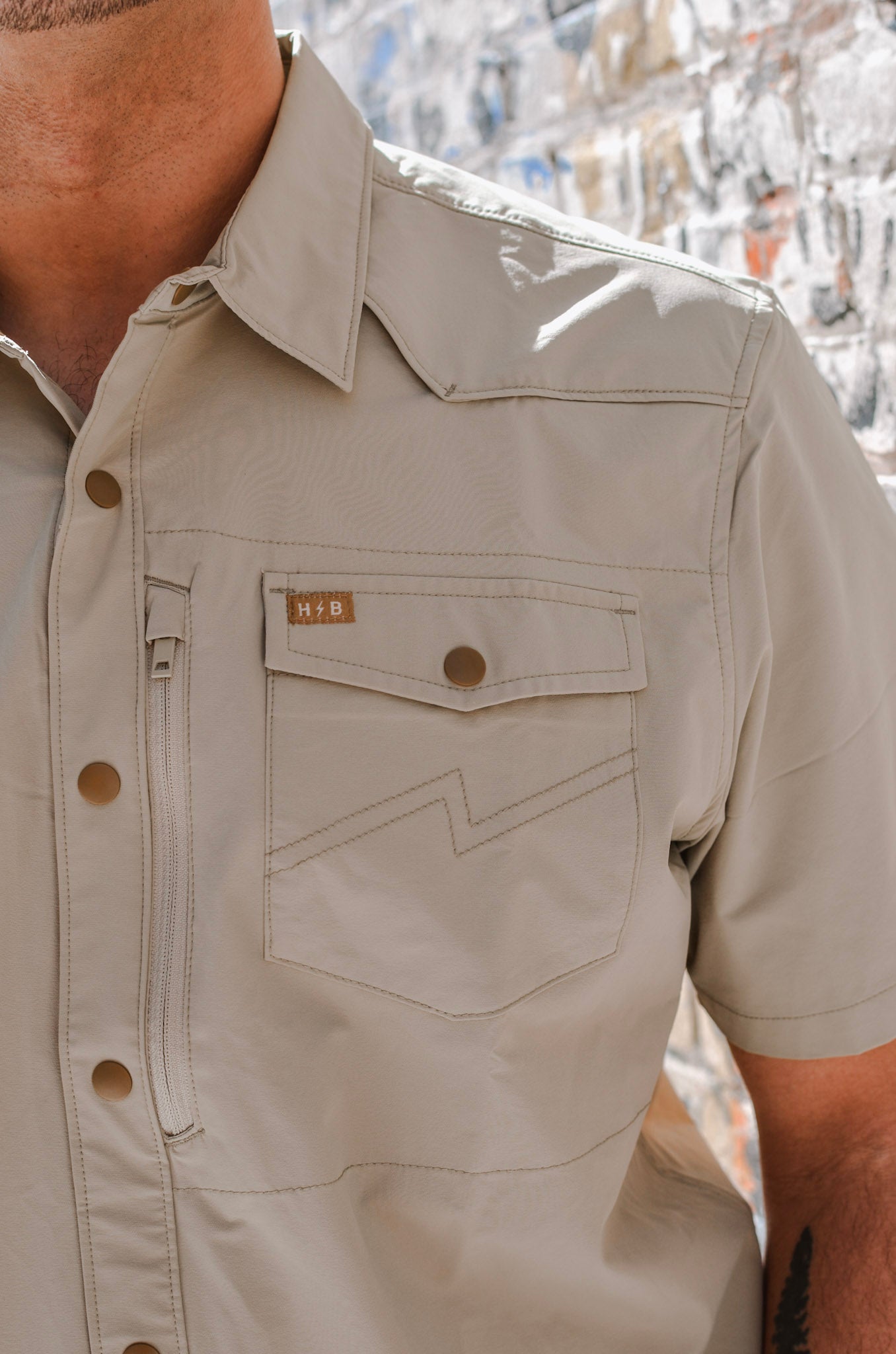 Beige short-sleeve shirt with brand logo on a textured background