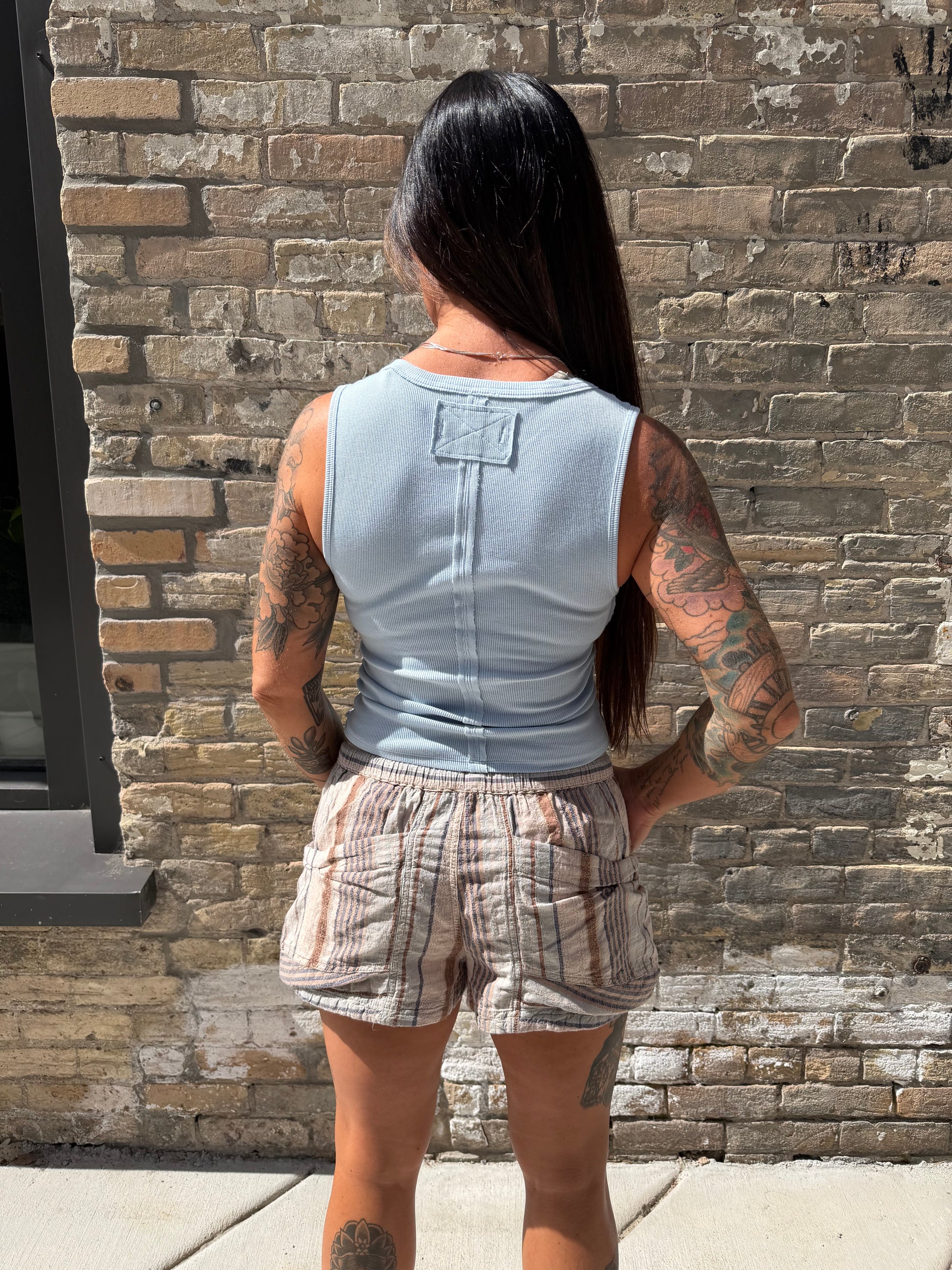 Person standing on a stone pavement with a brick wall background