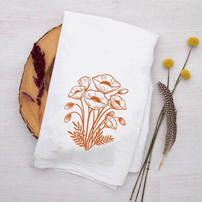 White towel with orange floral design on a wooden surface with decorative elements
