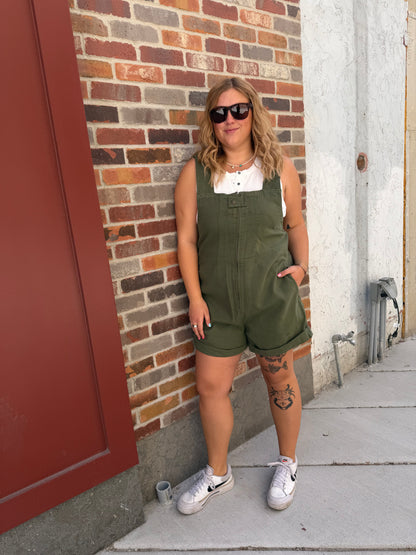 Person lying on a brick floor wearing a green dress and white sneakers.