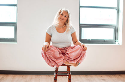 Woman sitting on a stool in a room with large windows