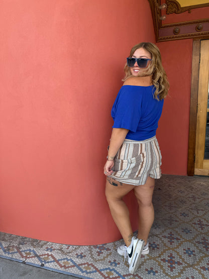 Person wearing a blue shirt and patterned skirt on a red carpet