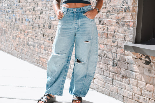 Person wearing wide-leg jeans with a brick wall background
