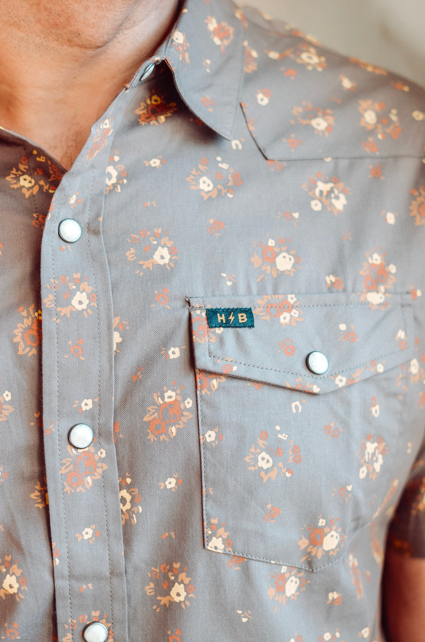Floral patterned shirt with a brand label on a neutral background