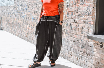 Person wearing a red shirt and black pants standing against a brick wall.