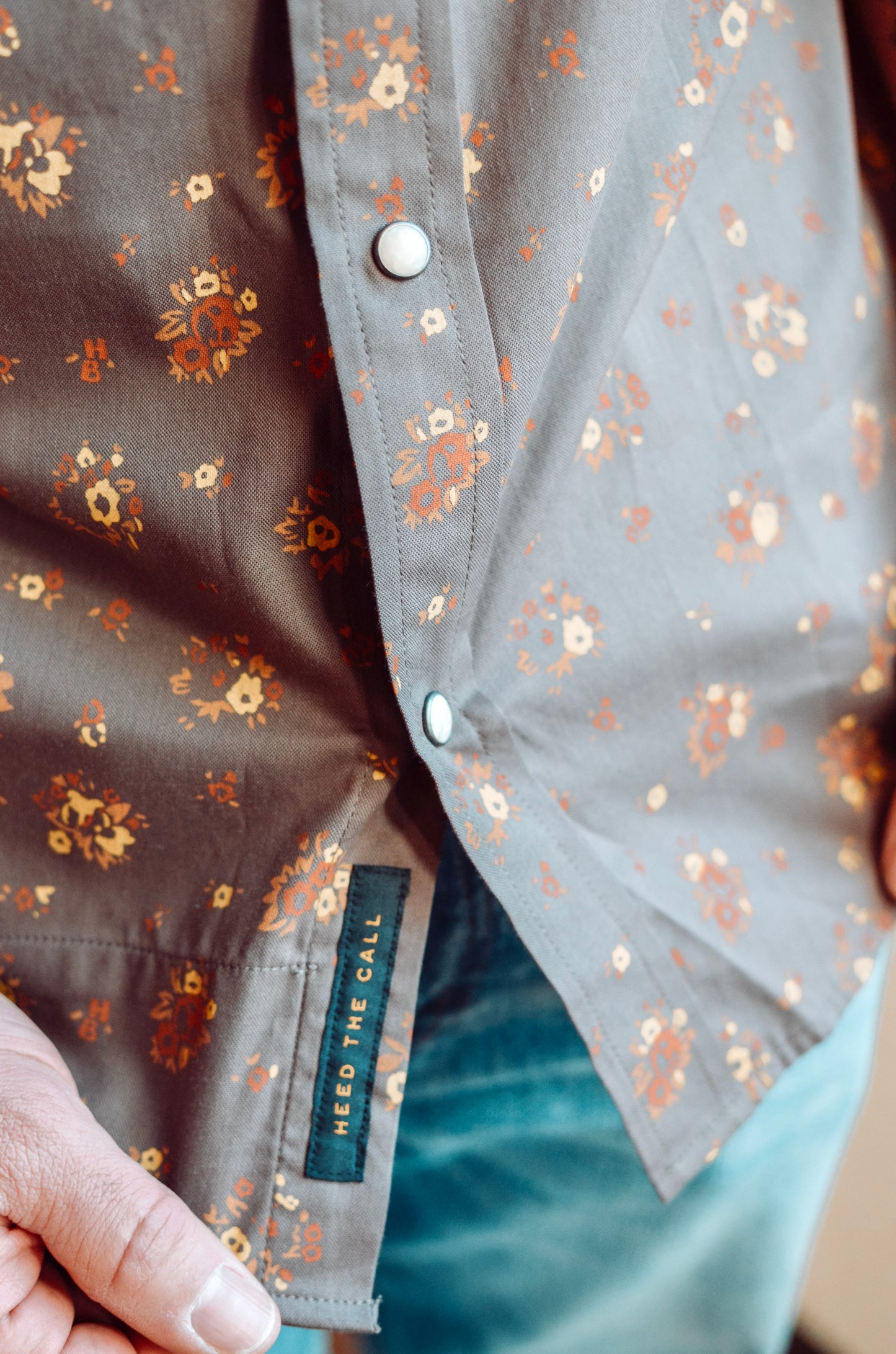Close-up of a shirt with floral pattern and 'Need The Call' label.