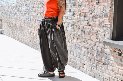 Person wearing a red top and black wide-leg pants standing against a brick wall.