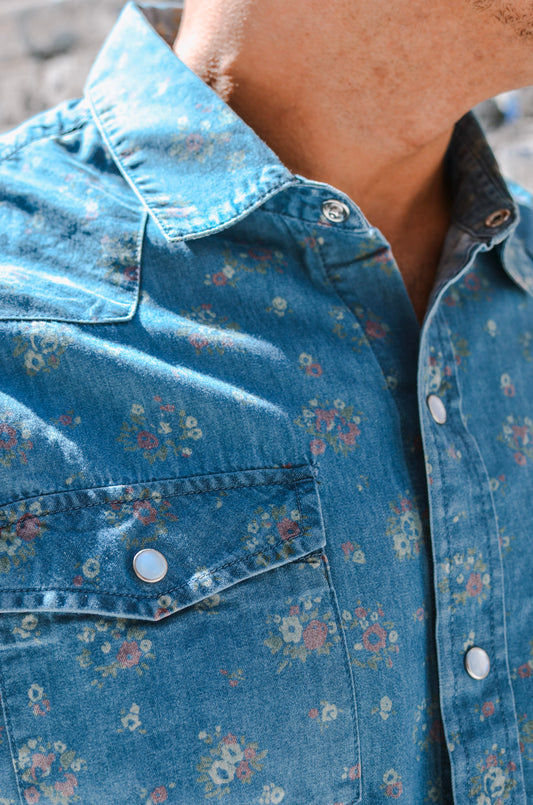 Close-up of a person wearing a blue floral denim shirt.