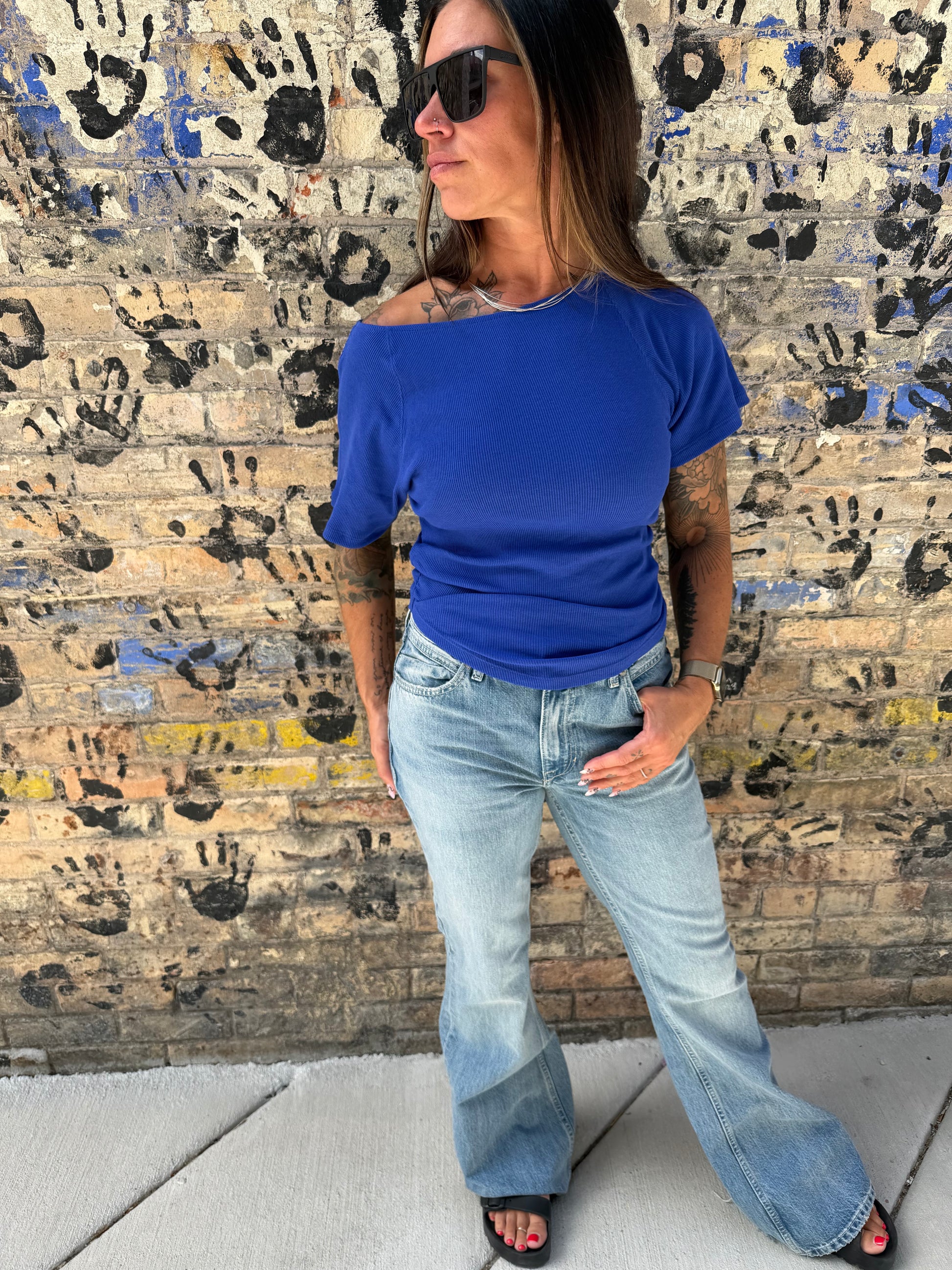 Woman in blue shirt and jeans standing on a textured floor.