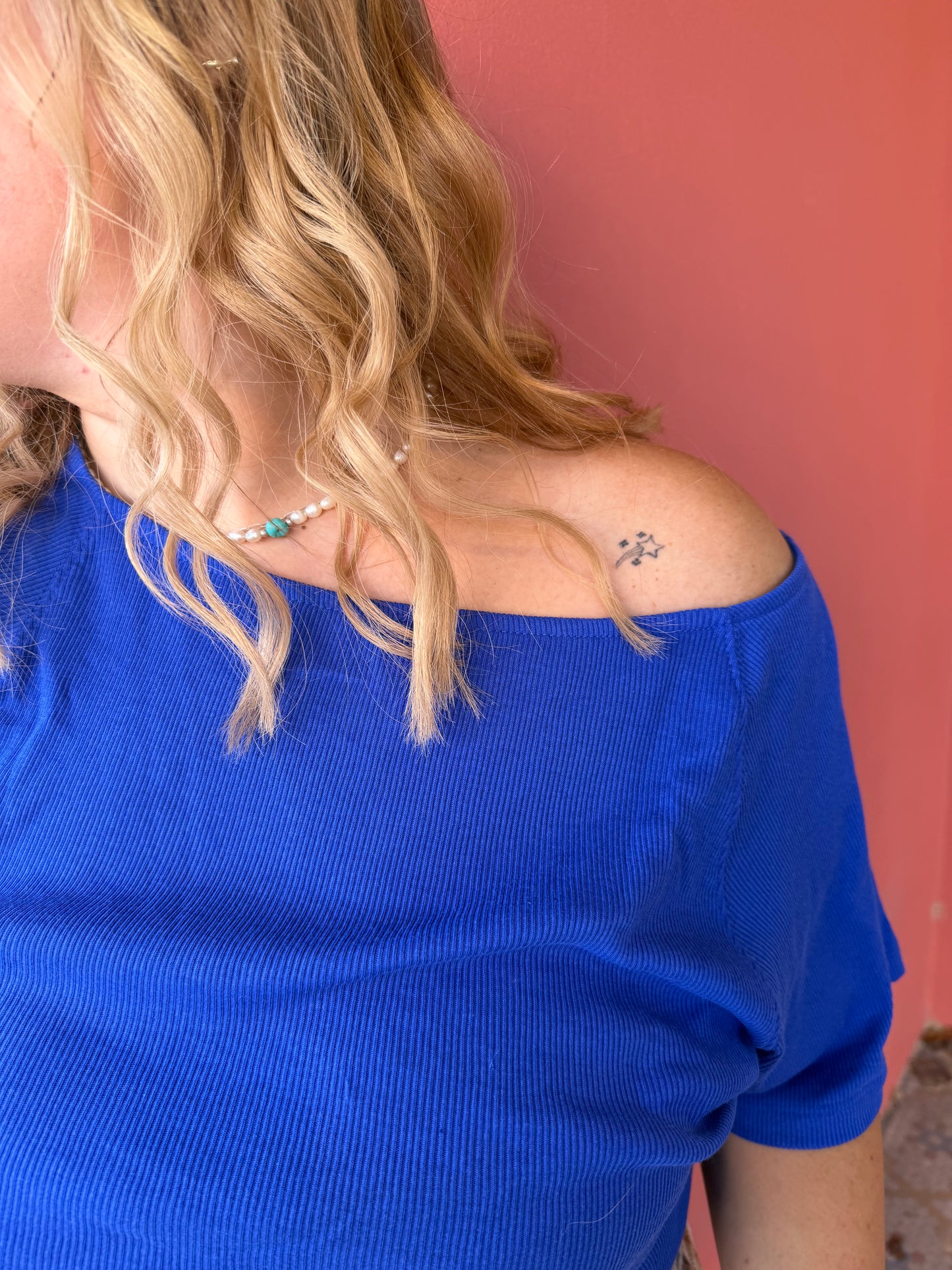 Person wearing a blue sleeveless top with a red background