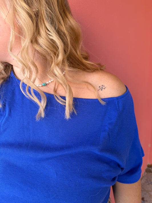 Person wearing a blue sleeveless top with a red background