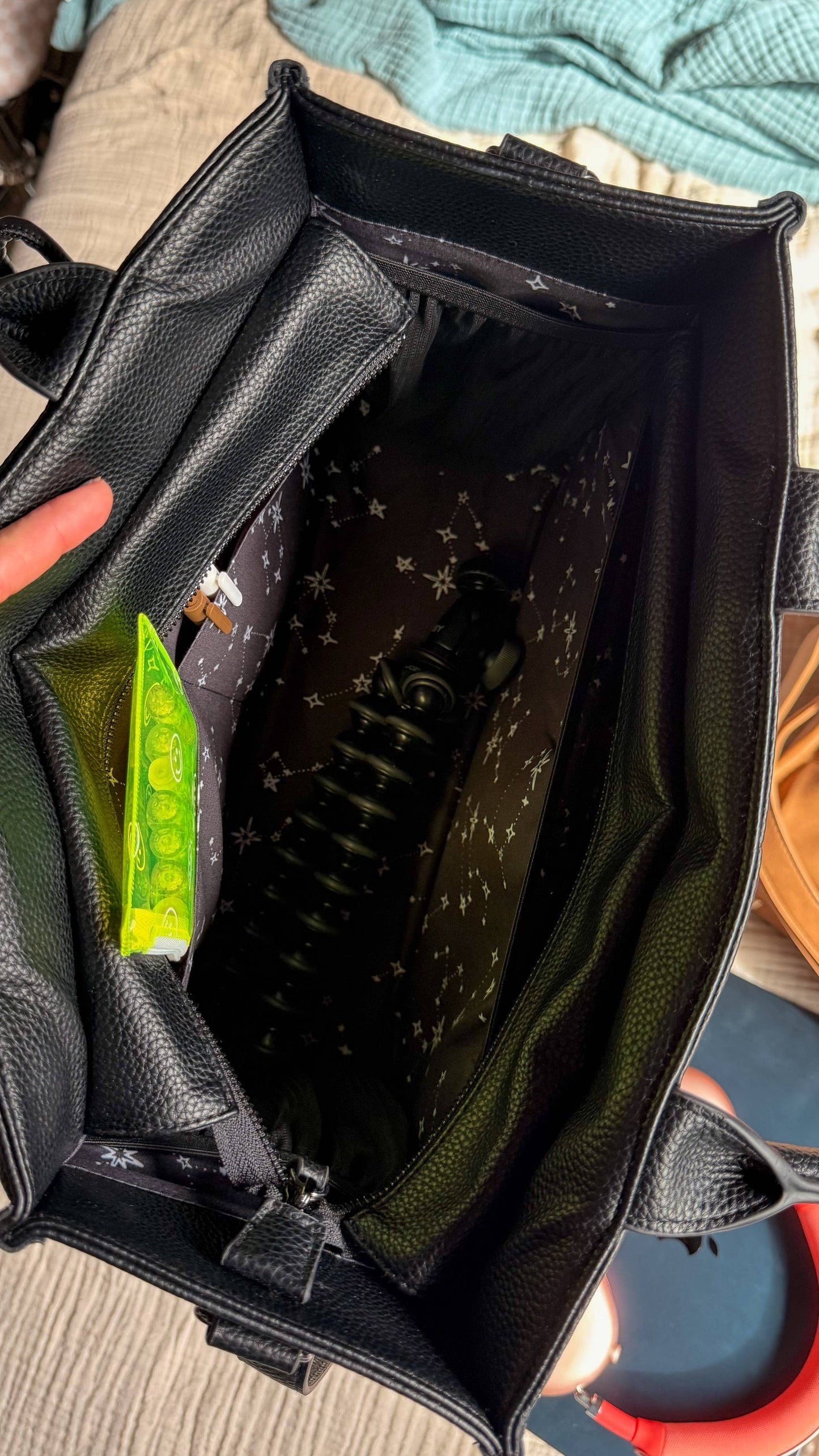 Black bag with a green snack packet inside, held by a hand.