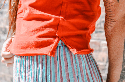 Person wearing an orange shirt and striped pants with a blurred background