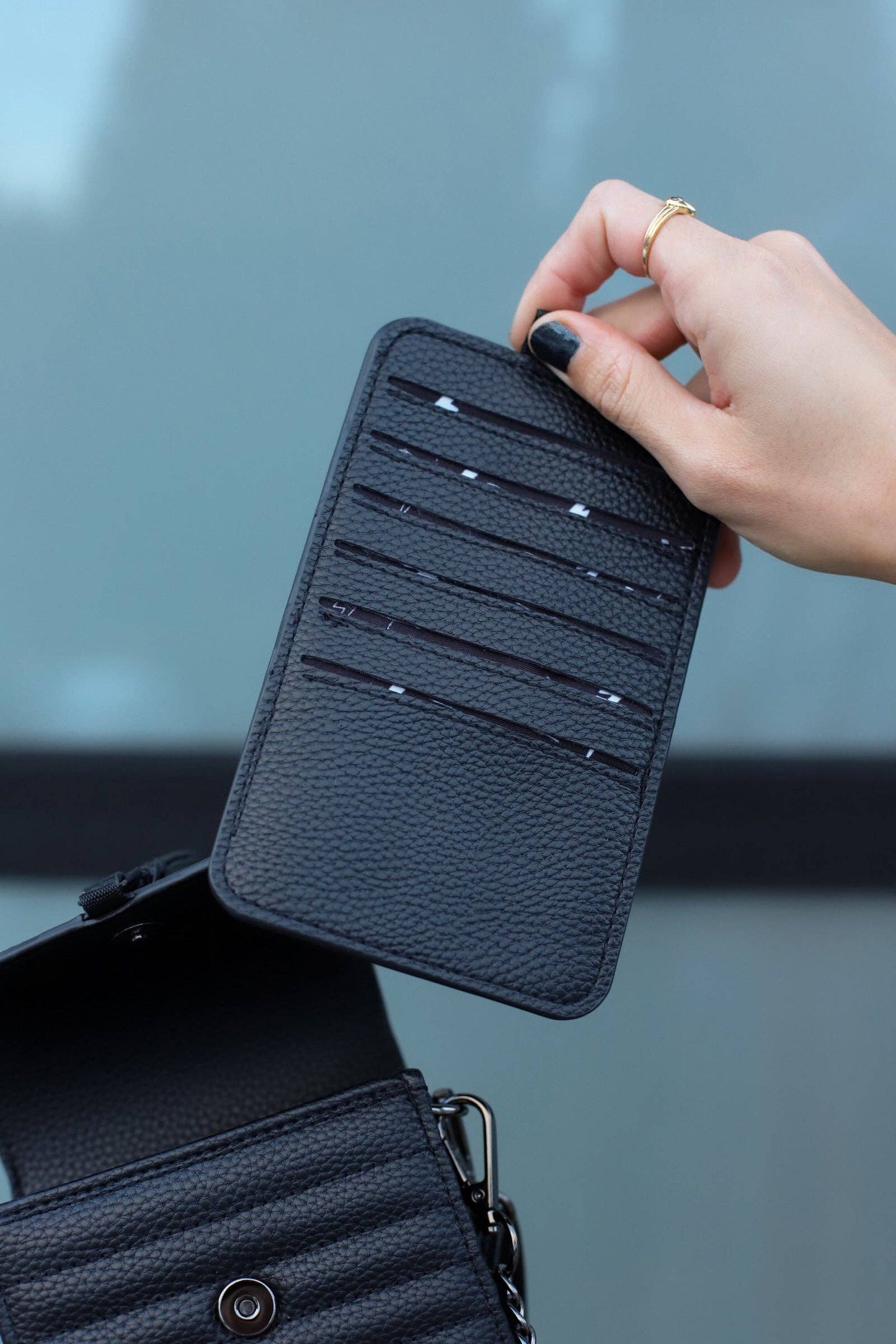 Hand holding a black leather cardholder with a blurred background