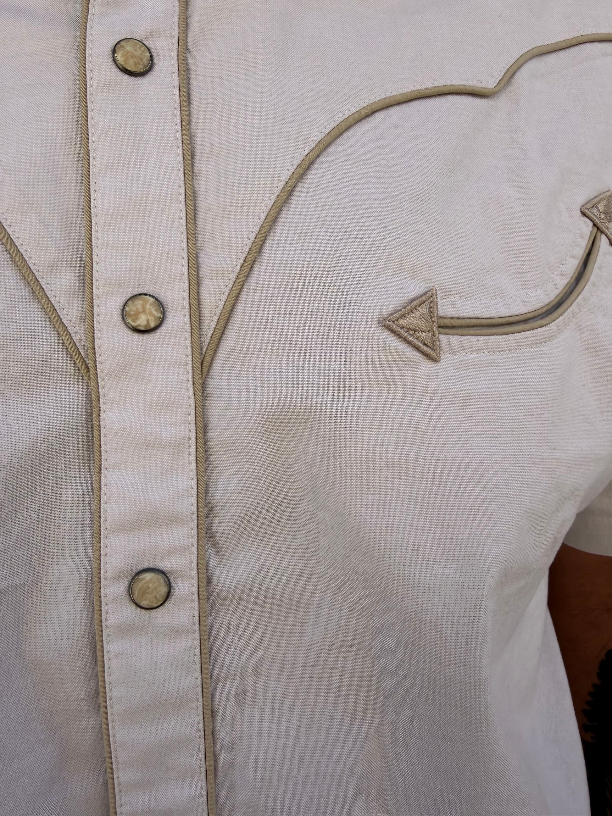 Close-up of a beige garment with decorative buttons and stitching