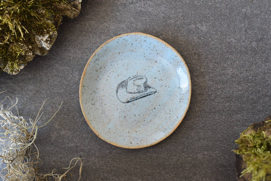 Ceramic plate with a hat design on a gray surface with natural elements.