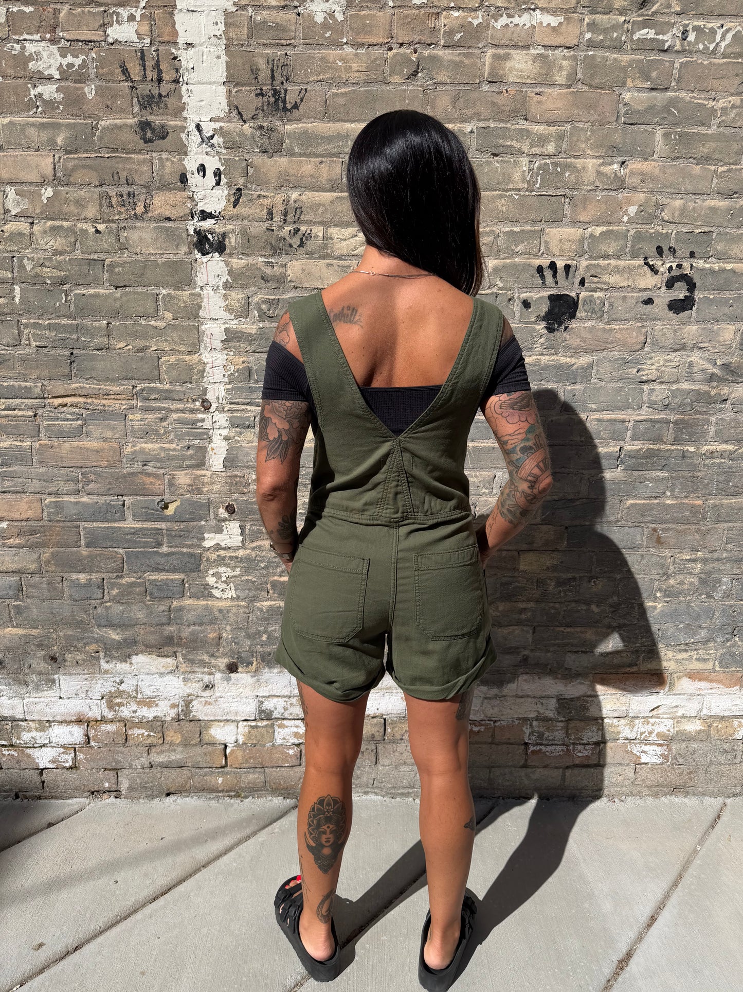 Person wearing green cargo shorts on a brick sidewalk