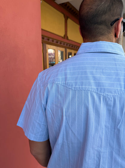 Person wearing a light blue shirt with a blurred background