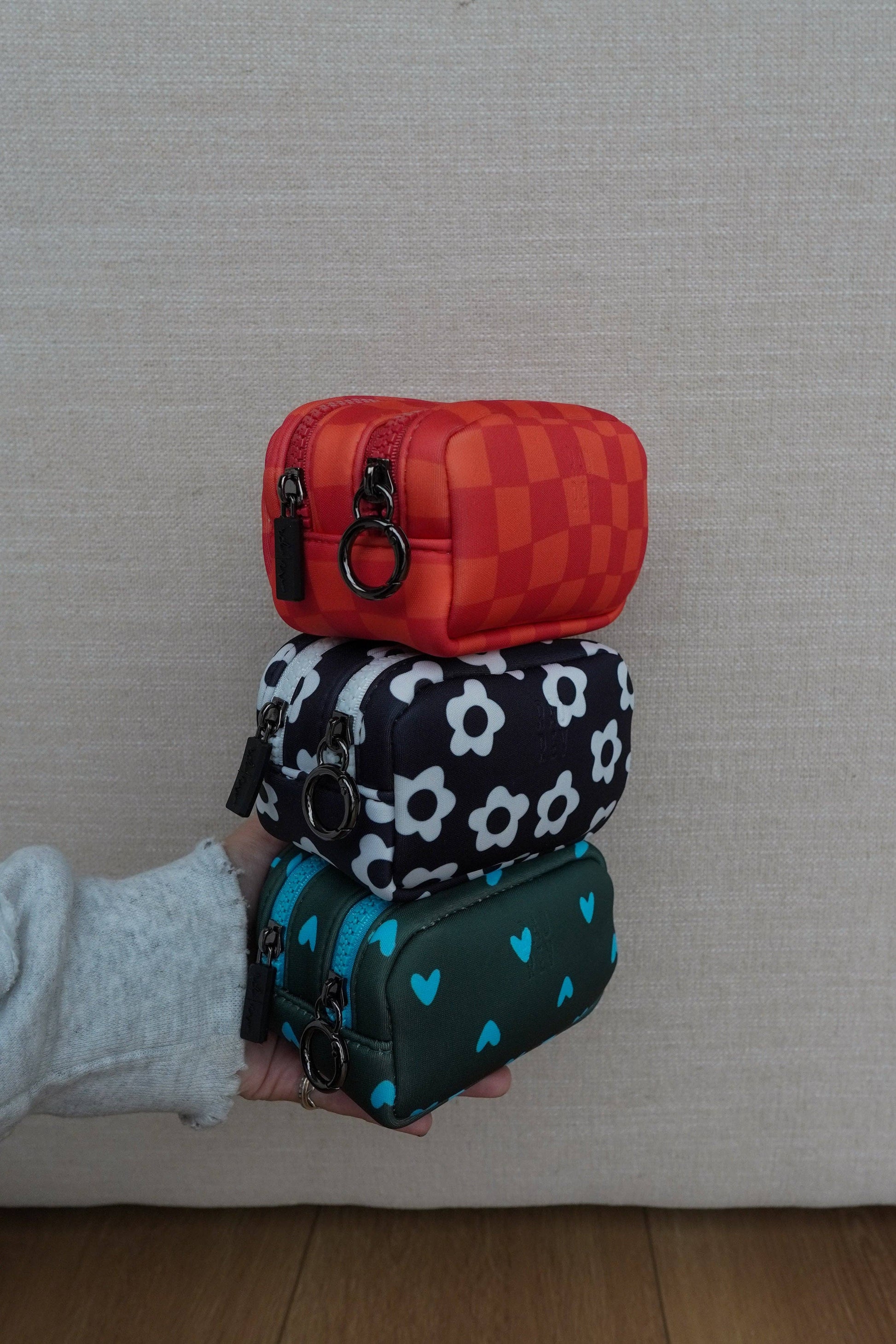 Stack of three patterned pouches held by a person against a neutral background