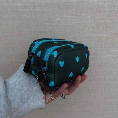 Black case with blue heart patterns held by a person against a beige background