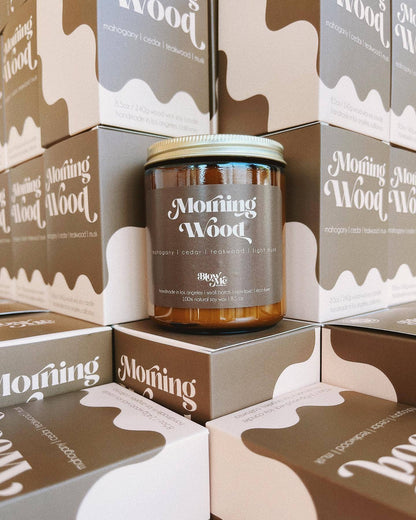Candle labeled 'Morning Wood' surrounded by branded boxes