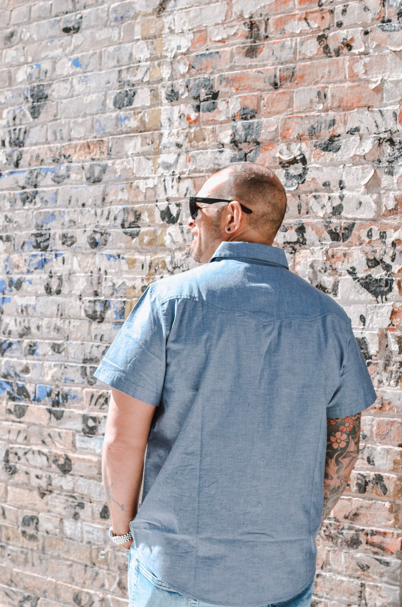 Man wearing a blue shirt against a textured brick wall