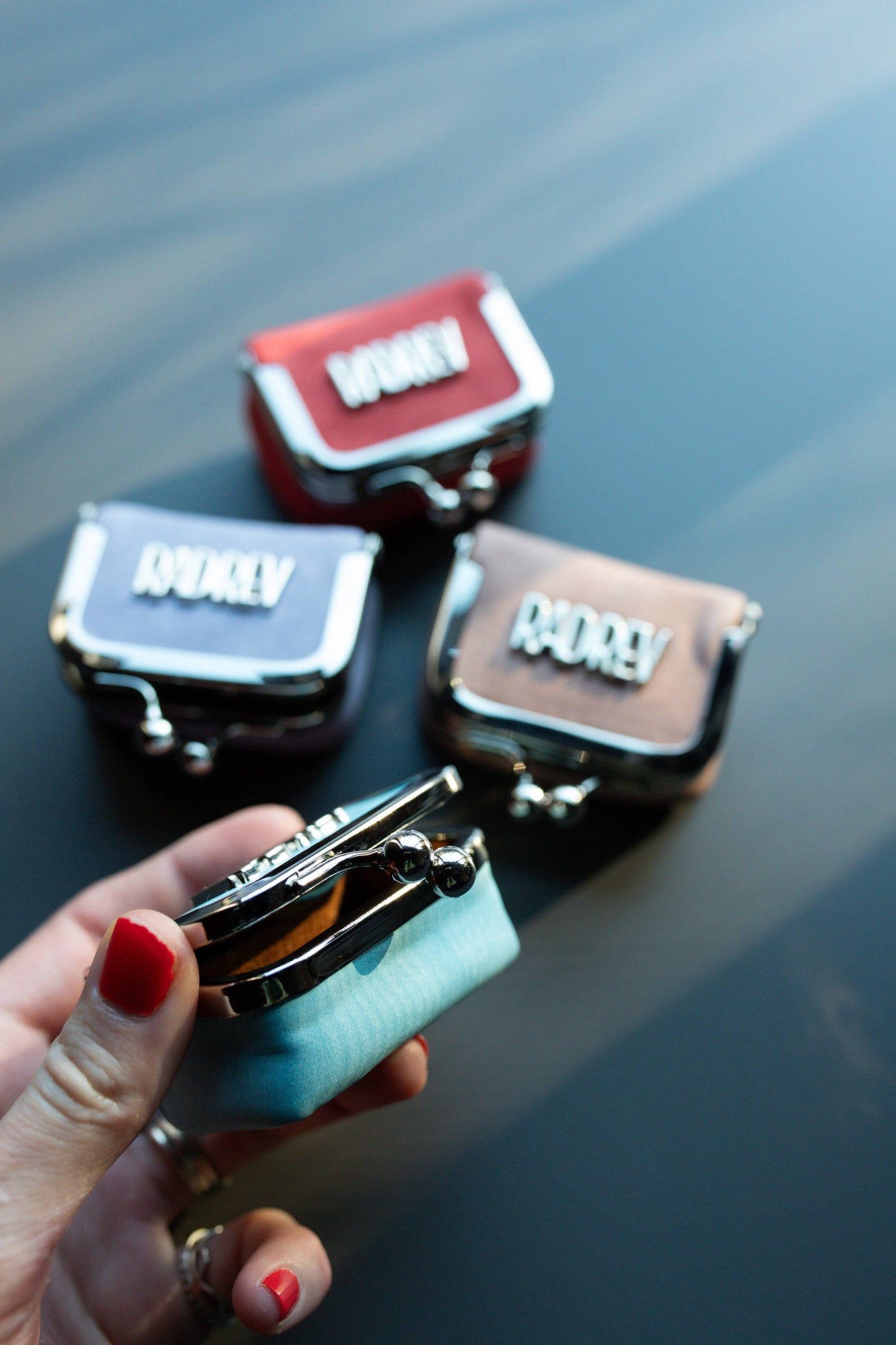 Set of small leather bags with visible brand names on a reflective surface.