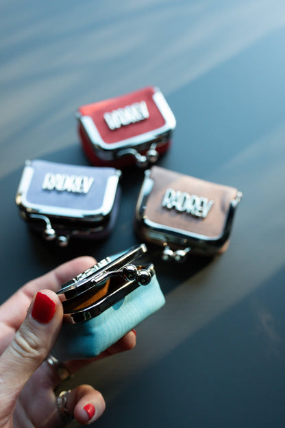 Set of small leather bags with visible brand names on a reflective surface.