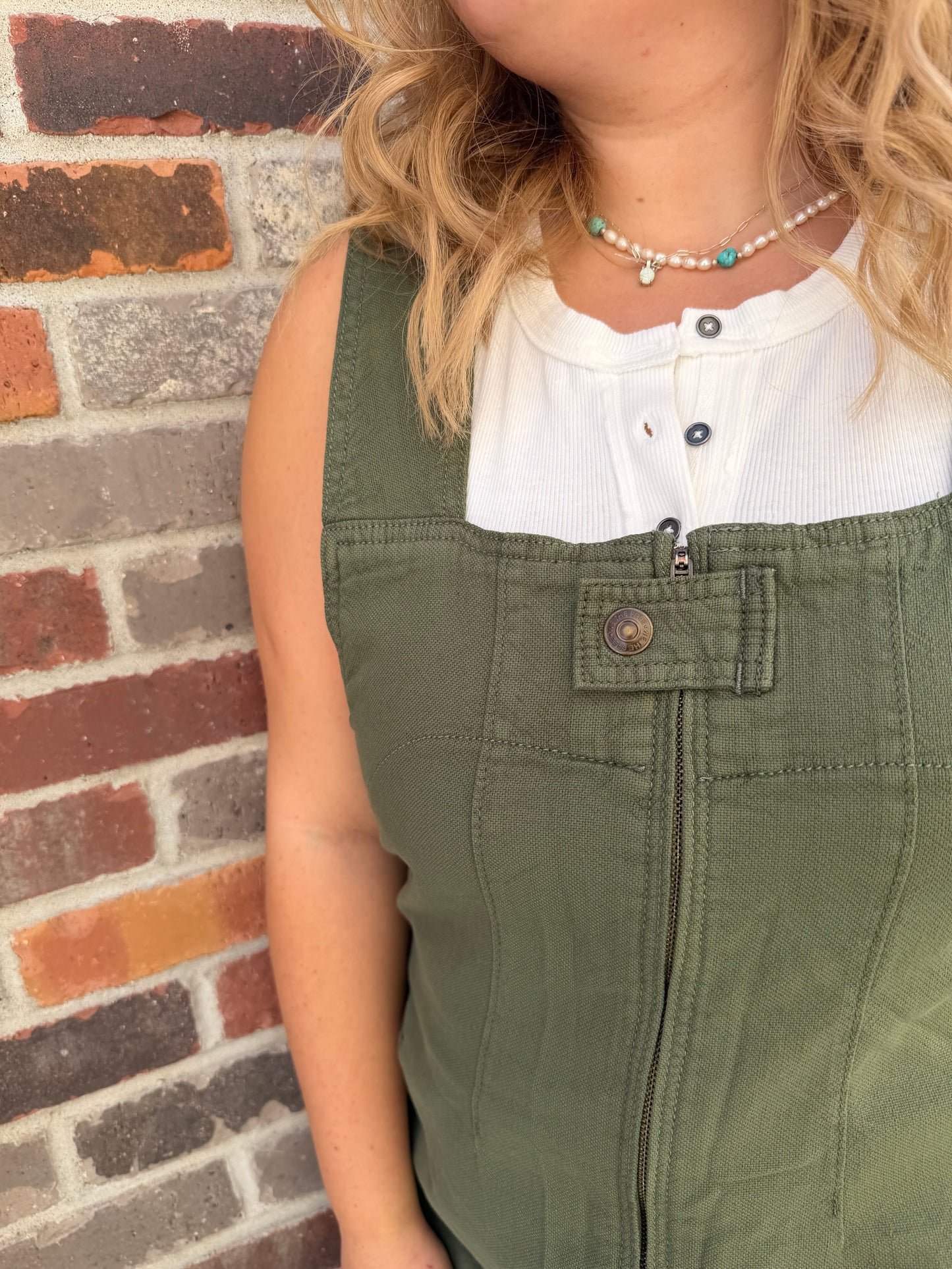 Person wearing green pants and a white shirt on a brick pavement