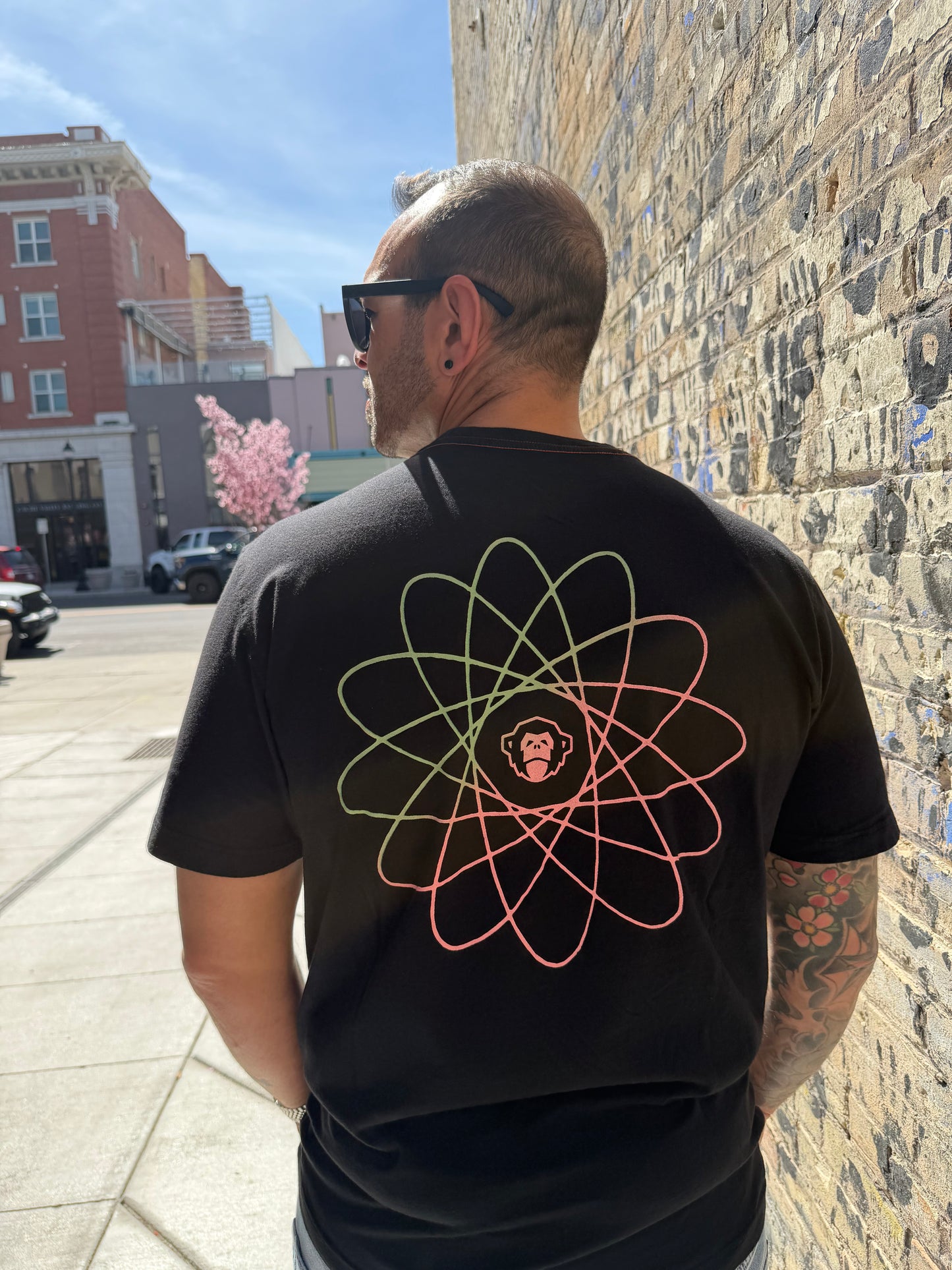 Person wearing a black hoodie with a geometric design outdoors on a sunny day.