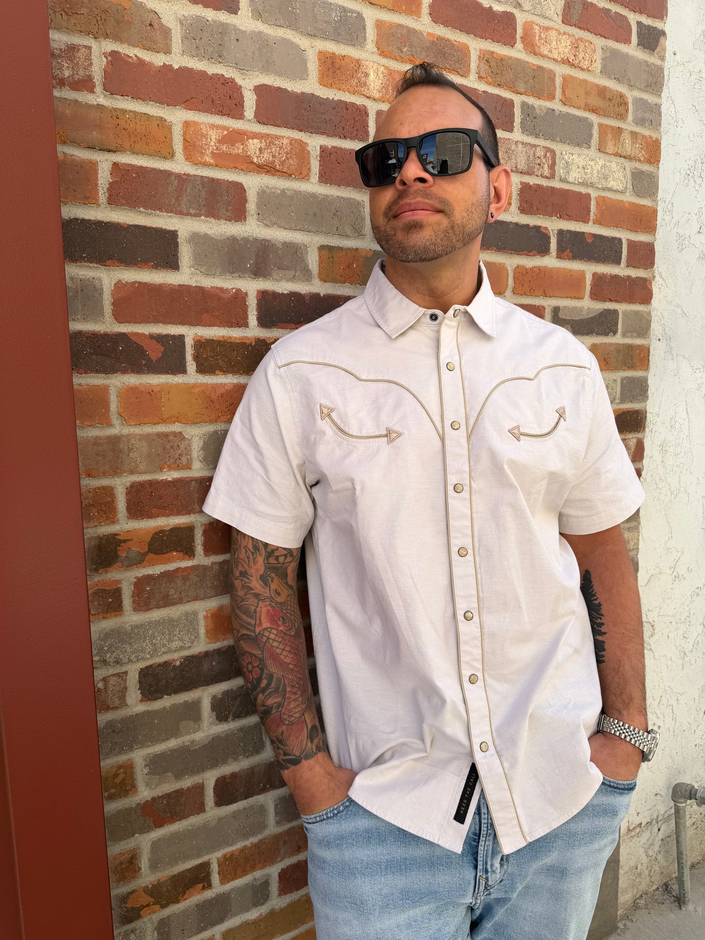 Man lying on a brick floor wearing a white shirt and sunglasses.