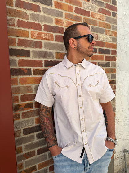 Man lying on a brick floor wearing a white shirt and sunglasses