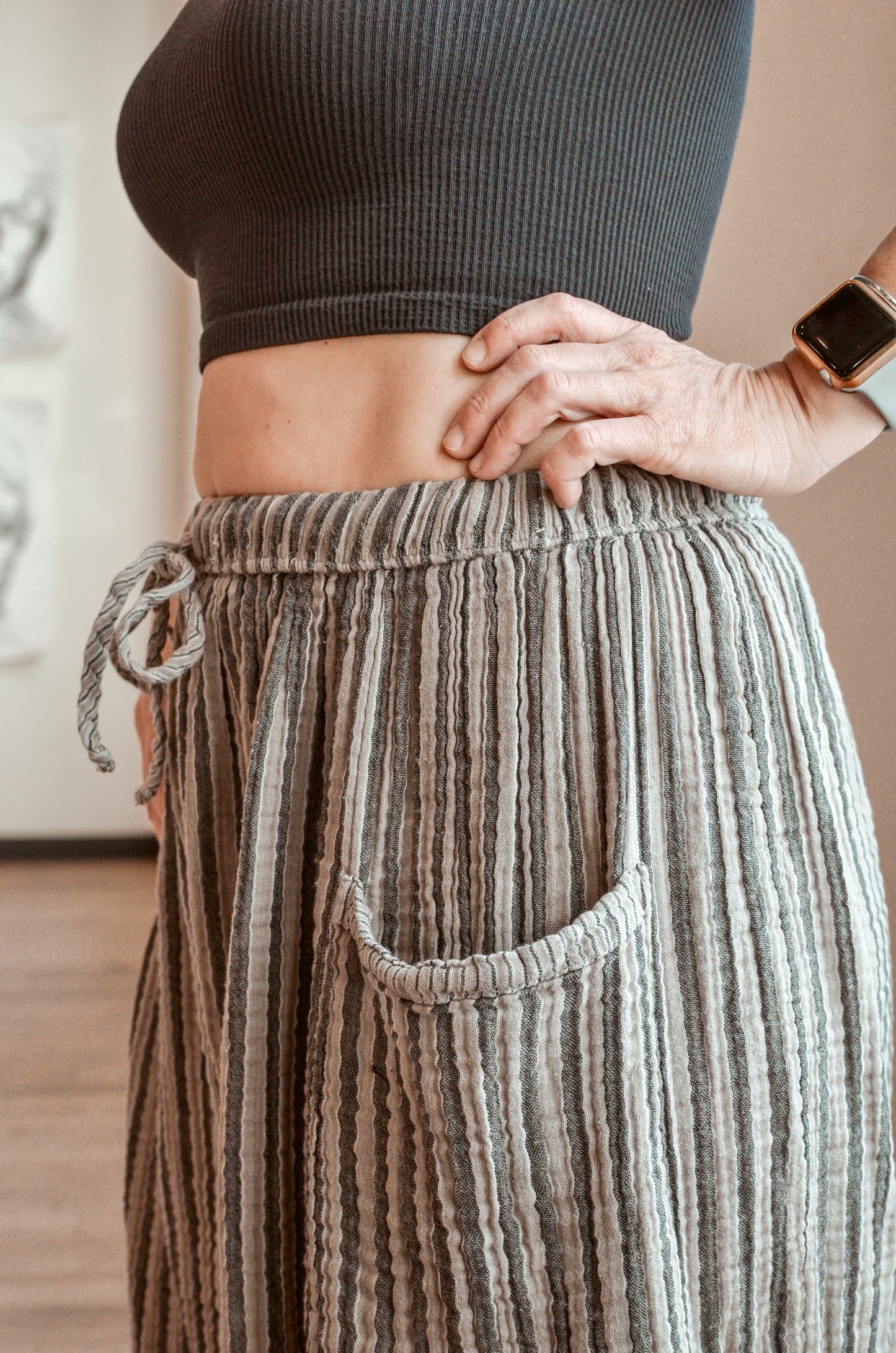 Person wearing a dark ribbed top and striped pants with a blurred background