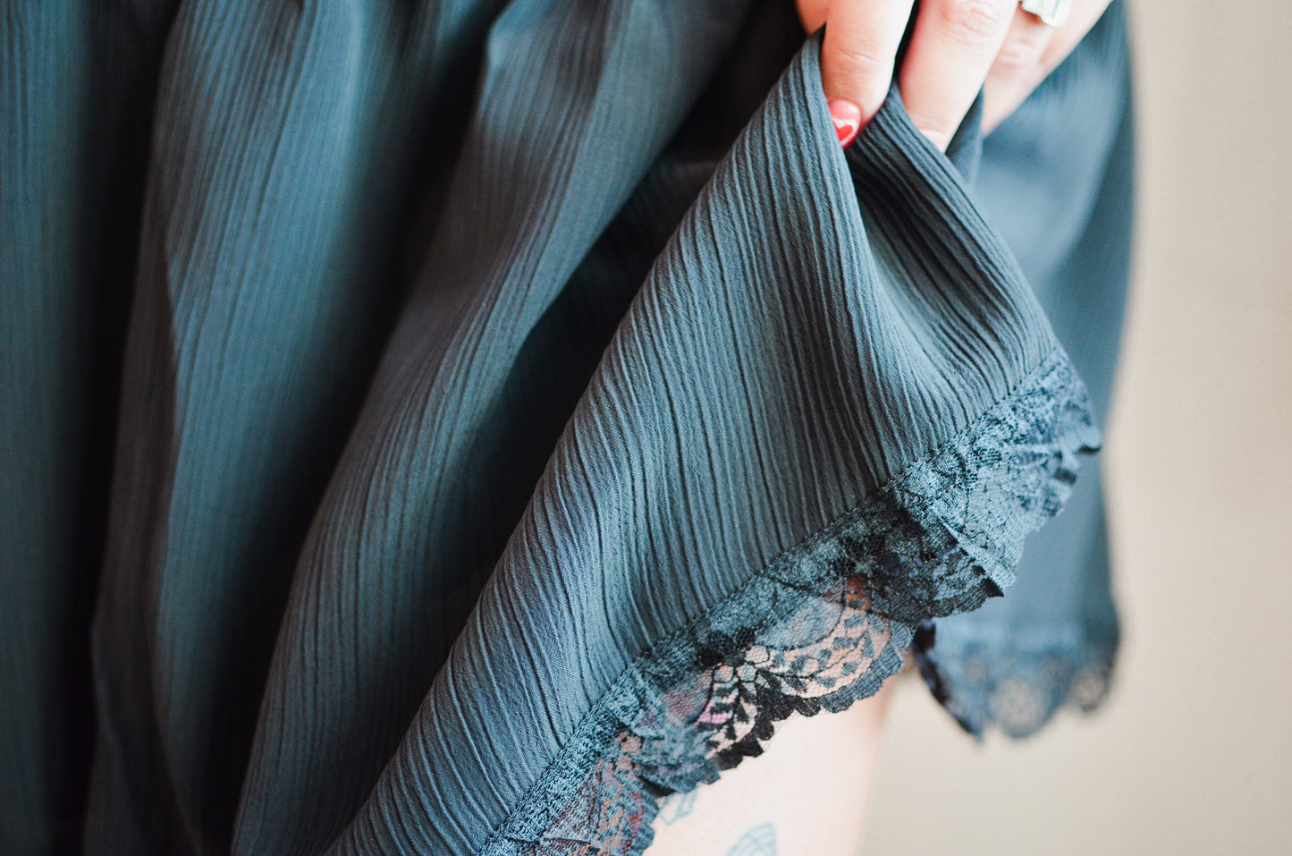 Close-up of a dark blue fabric with lace trim held by a hand.
