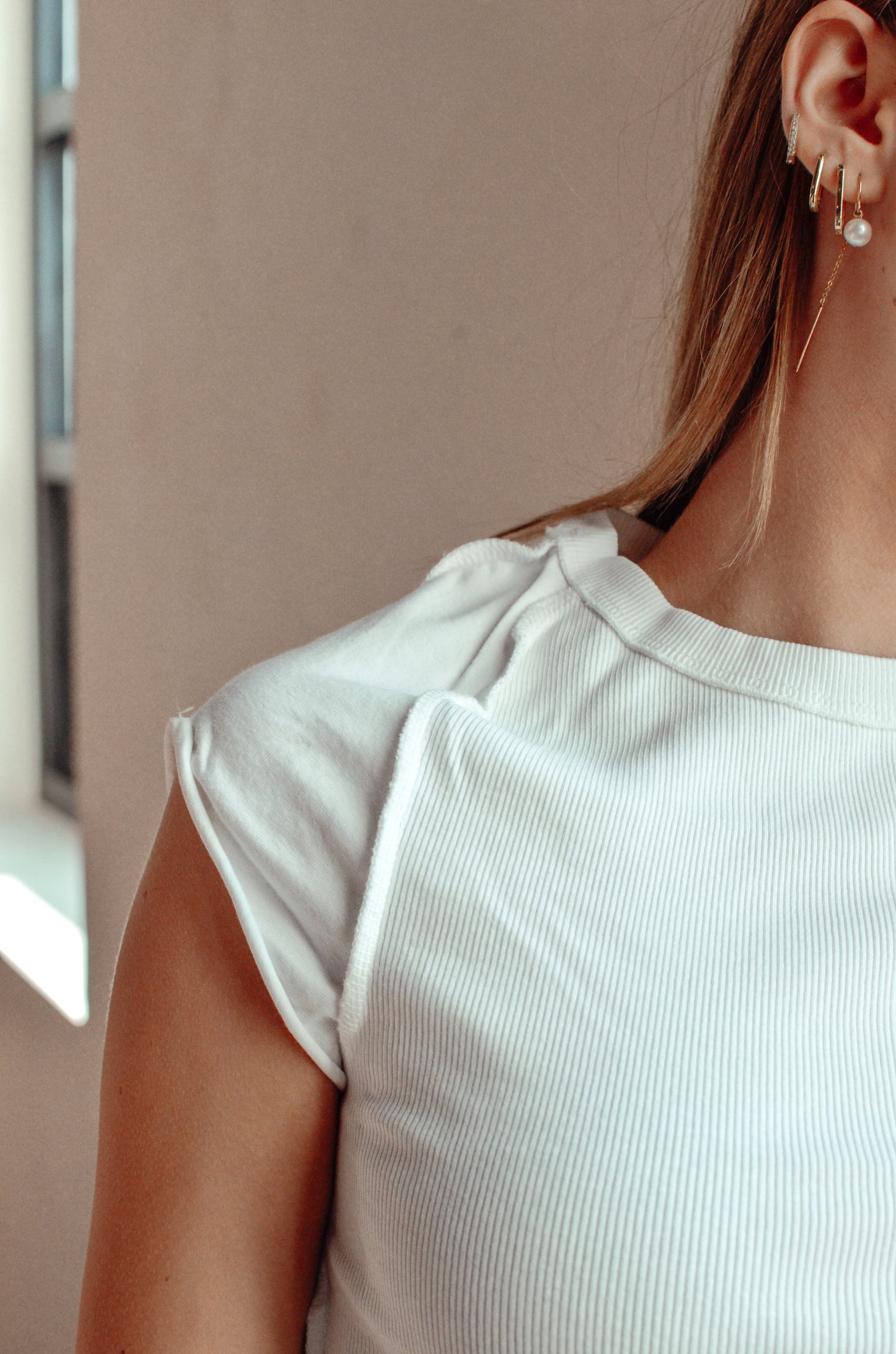 Close-up of a person wearing a light-colored top with a neutral background