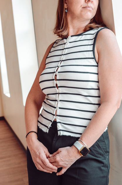 Person wearing a black and white striped sleeveless top with a neutral background
