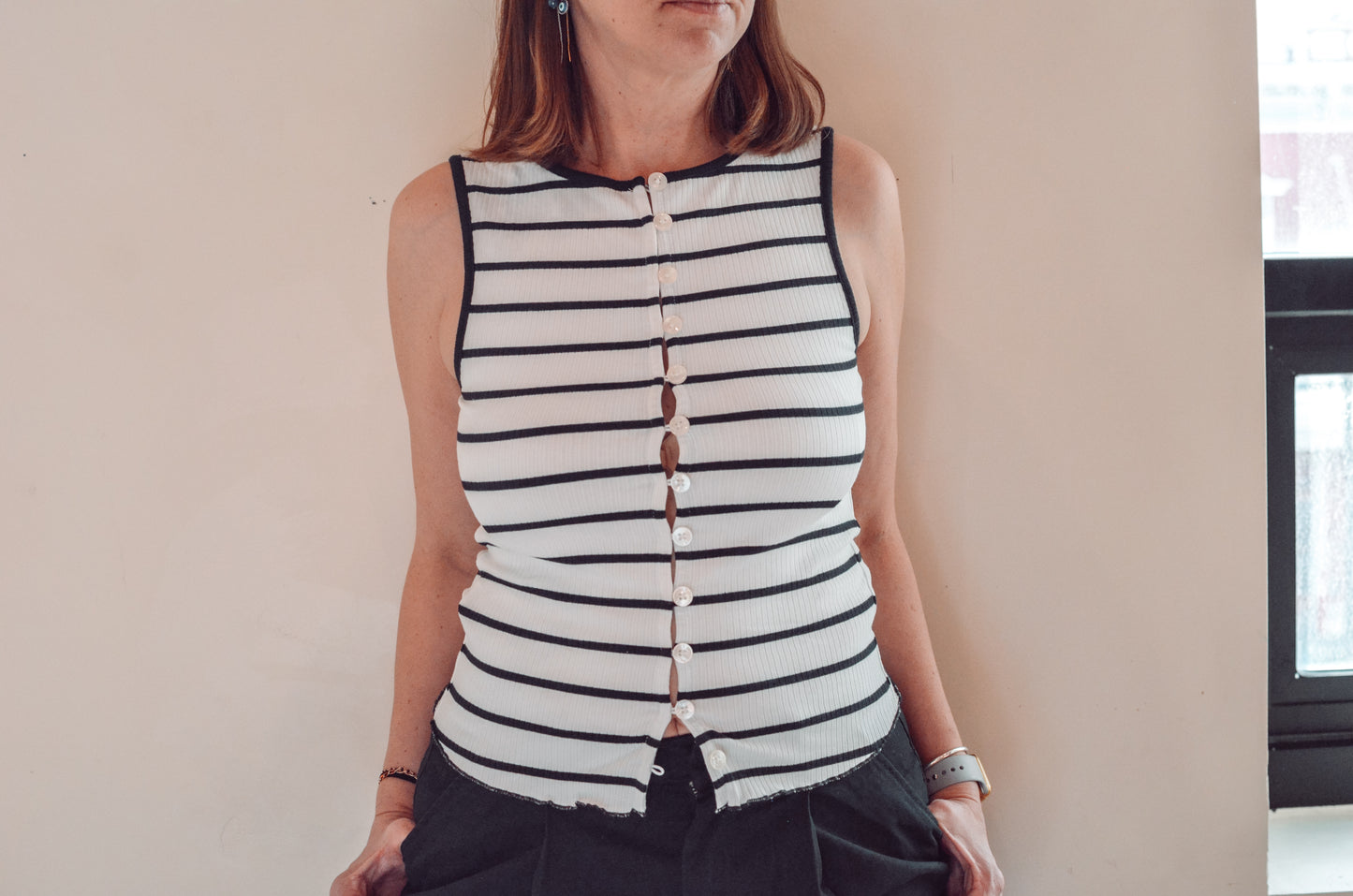 Person wearing a black and white striped sleeveless top against a neutral background