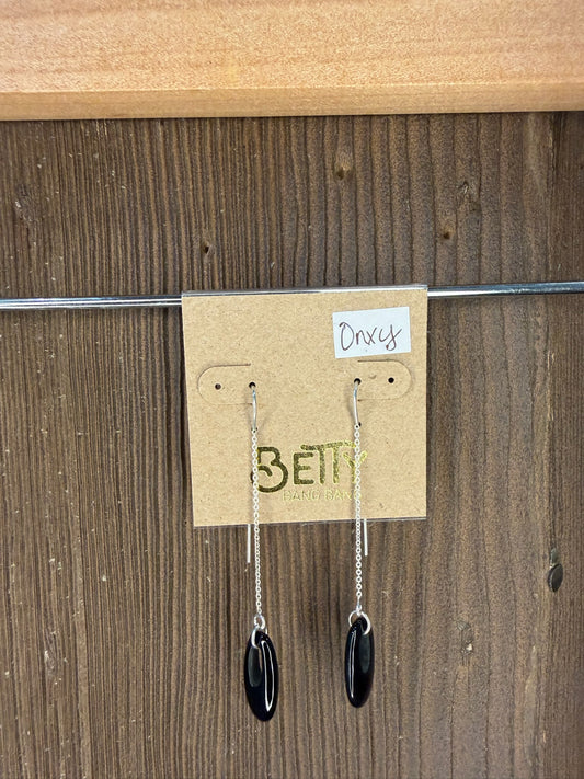 Pair of earrings on a 'Bella' branded card against a wooden background