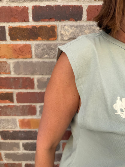 Person wearing a light blue shirt on a brick floor